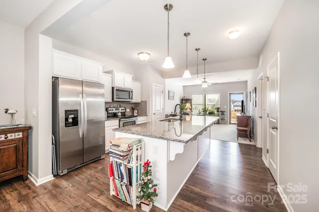 a view of a kitchen with kitchen island a counter top space a sink a refrigerator and a stove