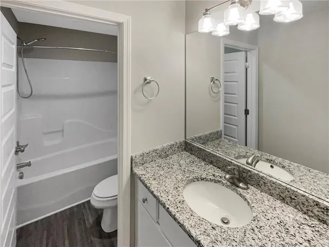 a bathroom with a granite countertop sink toilet and shower