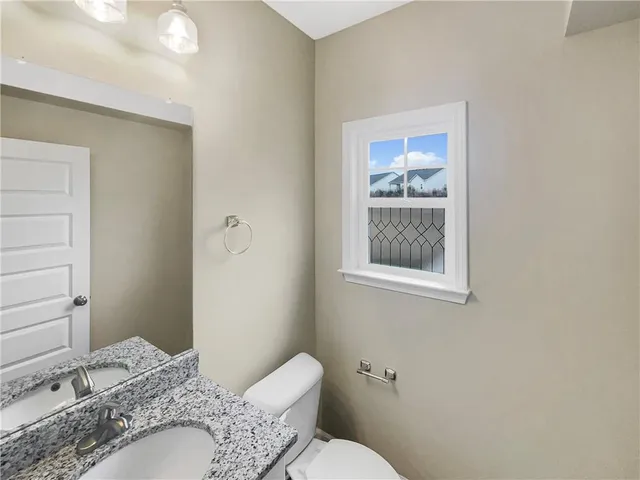 a bathroom with a granite countertop toilet sink and mirror