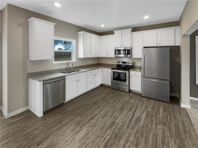a kitchen with a sink wooden floor and stainless steel appliances