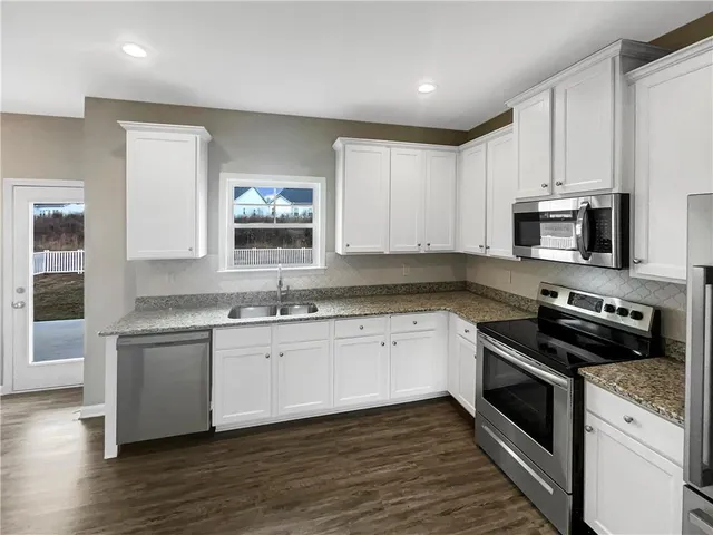 a kitchen with stainless steel appliances granite countertop a stove a sink and a microwave