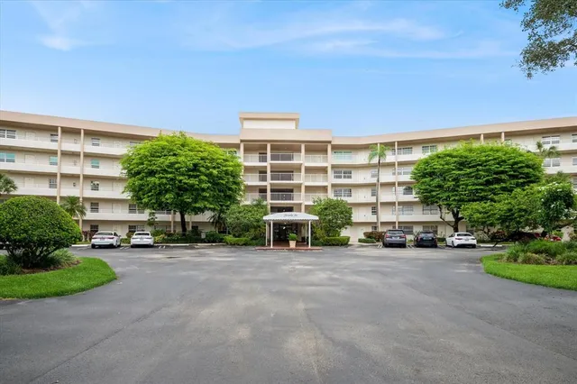 a view of a building with a garden and parking space