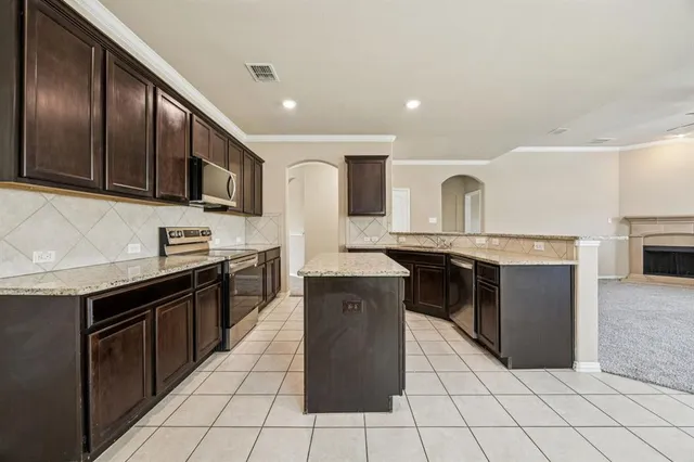 a kitchen with stainless steel appliances granite countertop a stove a sink and a microwave