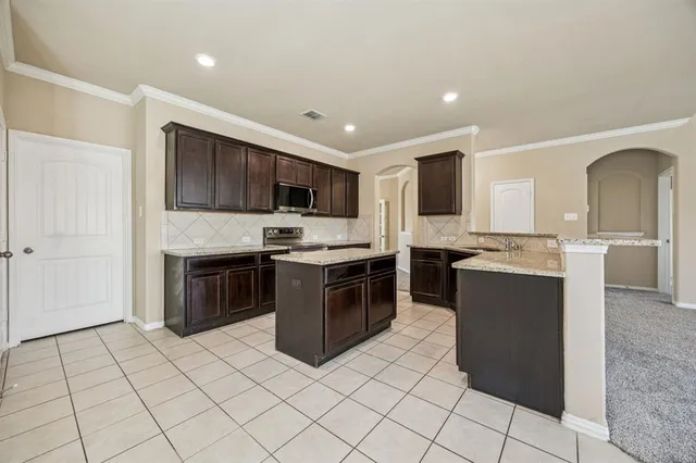 a large kitchen with kitchen island granite countertop a sink and a stove top oven