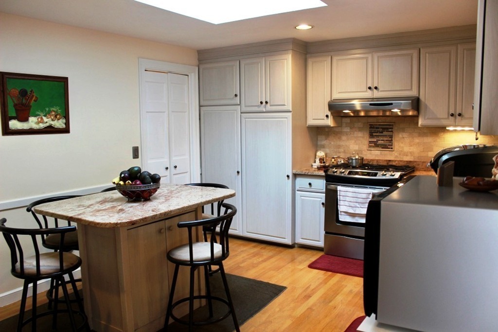 20 Poplar Road Wellesley, MA 02482 - Photo 9 of 27 a kitchen with stainless steel appliances granite countertop a stove a refrigerator a sink a dining table and chairs with wooden floor