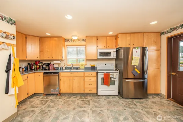 a kitchen with stainless steel appliances granite countertop a refrigerator a stove and a sink