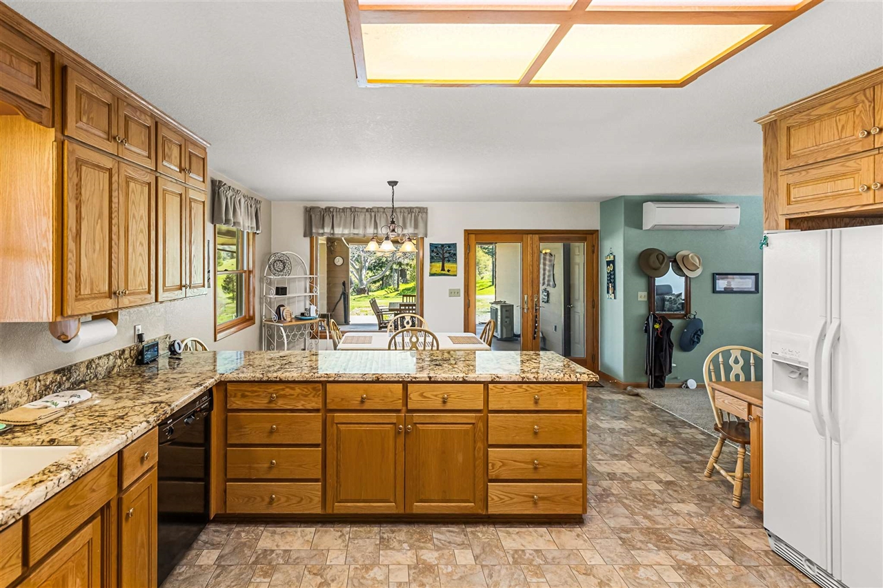 16554 Cocoran Gray Road Groveland, CA 95321 - Photo 12 of 38 Kitchen with decorative light fixtures, light stone counters, white refrigerator with ice dispenser, and light tile flooring