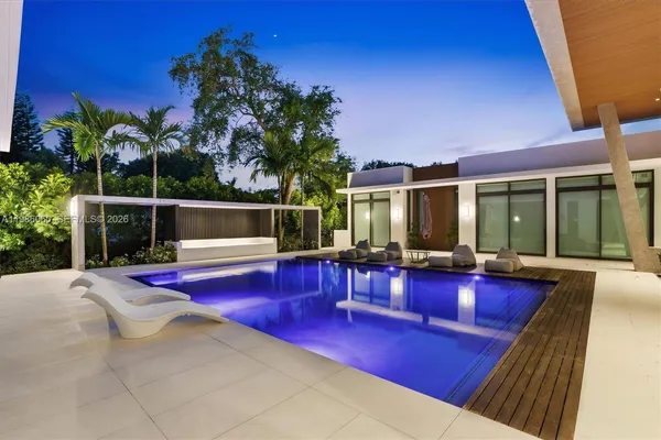 a view of swimming pool with outdoor seating and house in the background