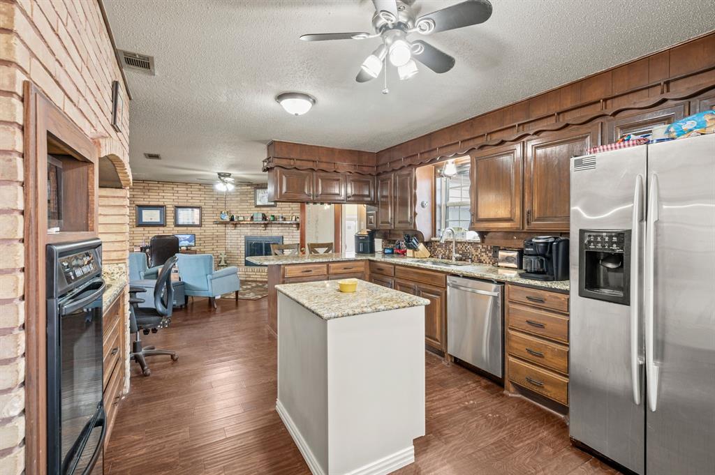 2125 Shady Brook Drive Bedford, TX 76021 - Photo 9 of 24 a kitchen with stainless steel appliances granite countertop a refrigerator a sink dishwasher a stove and a dining table with wooden floor