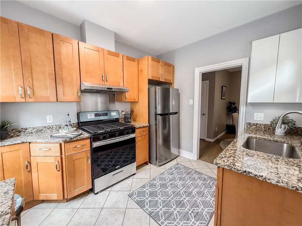 5642 Solway Street Pittsburgh, PA 15217 - Photo 14 of 28 a kitchen with granite countertop a sink stove and refrigerator