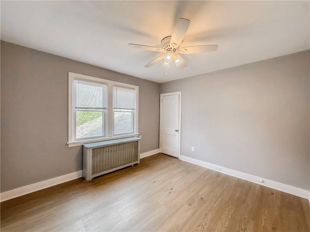 5642 Solway Street Pittsburgh, PA 15217 - Photo 22 of 28 an empty room with wooden floor chandelier fan and windows
