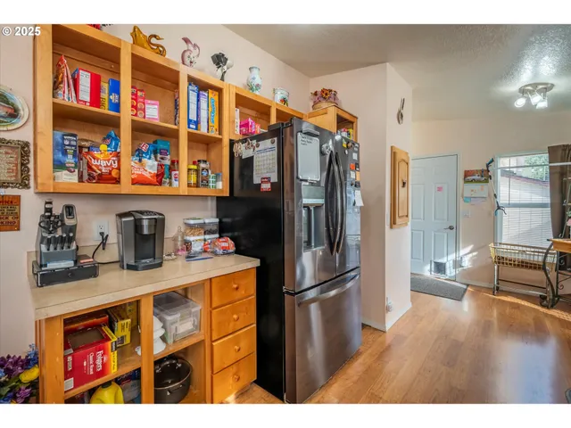 a kitchen with stainless steel appliances granite countertop a refrigerator and a wooden floor