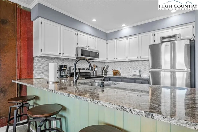 a kitchen with stainless steel appliances granite countertop a sink refrigerator and cabinets