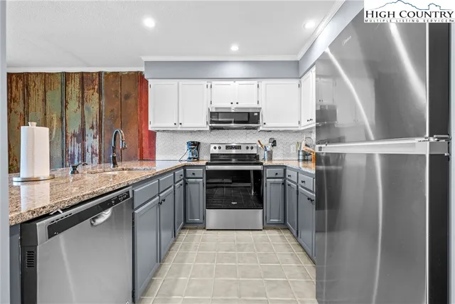 a kitchen with stainless steel appliances granite countertop a refrigerator a stove and a sink