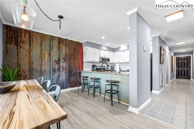 a open kitchen with stainless steel appliances granite countertop a refrigerator a oven a sink with wooden cabinets and wooden floor