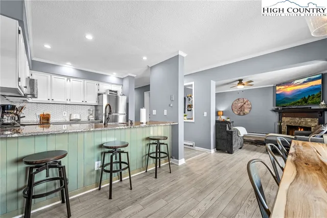 a kitchen with stainless steel appliances granite countertop a table chairs stove a sink dishwasher and cabinets with wooden floor