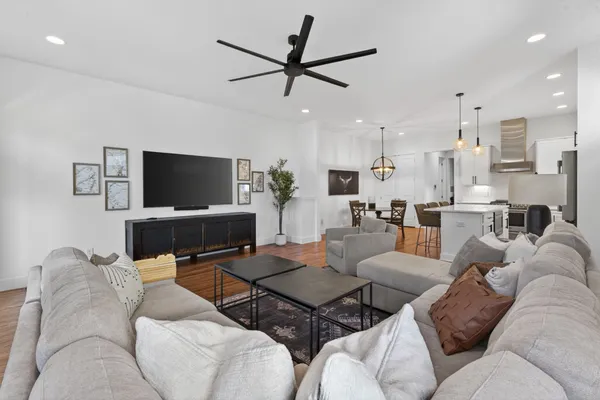 a kitchen with stainless steel appliances granite countertop a stove a refrigerator a kitchen island a dining table and chairs with wooden floor