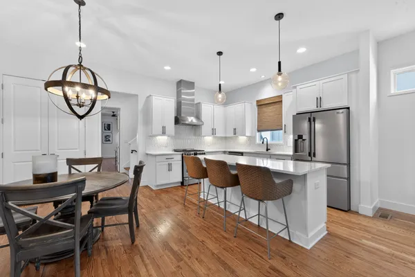 a kitchen with stainless steel appliances granite countertop a stove a refrigerator a sink a dining table and chairs
