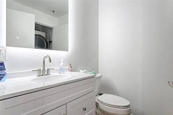 a bathroom with a toilet a sink a mirror and vanity