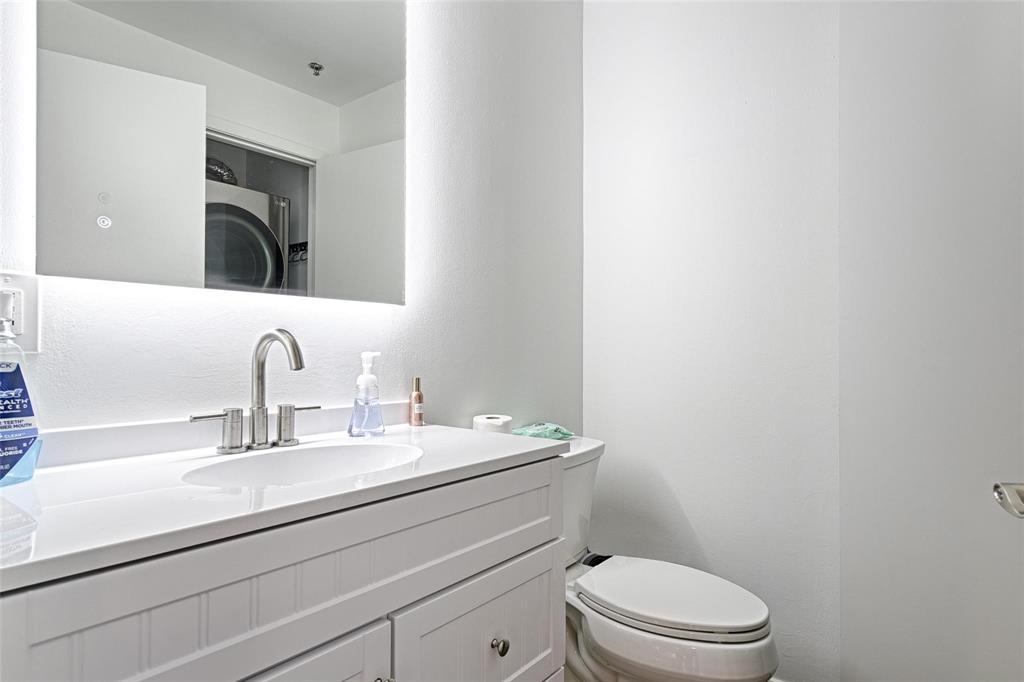 1001 Belleview Street, Unit 104 Dallas, TX 75215 - Photo 17 of 22 a bathroom with a toilet a sink a mirror and vanity