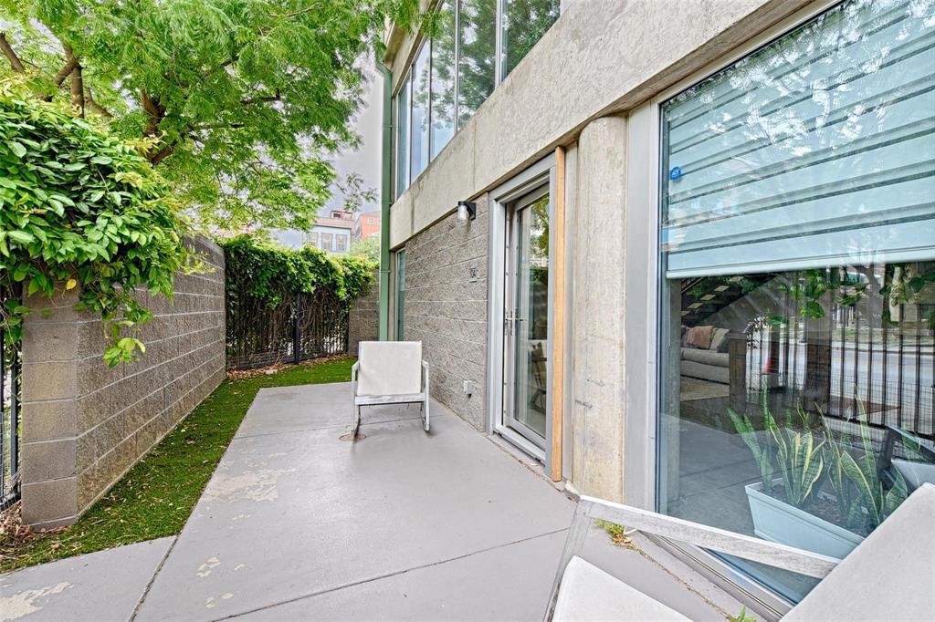1001 Belleview Street, Unit 104 Dallas, TX 75215 - Photo 5 of 22 a view of a patio with table and chairs and floor to ceiling window with wooden fence