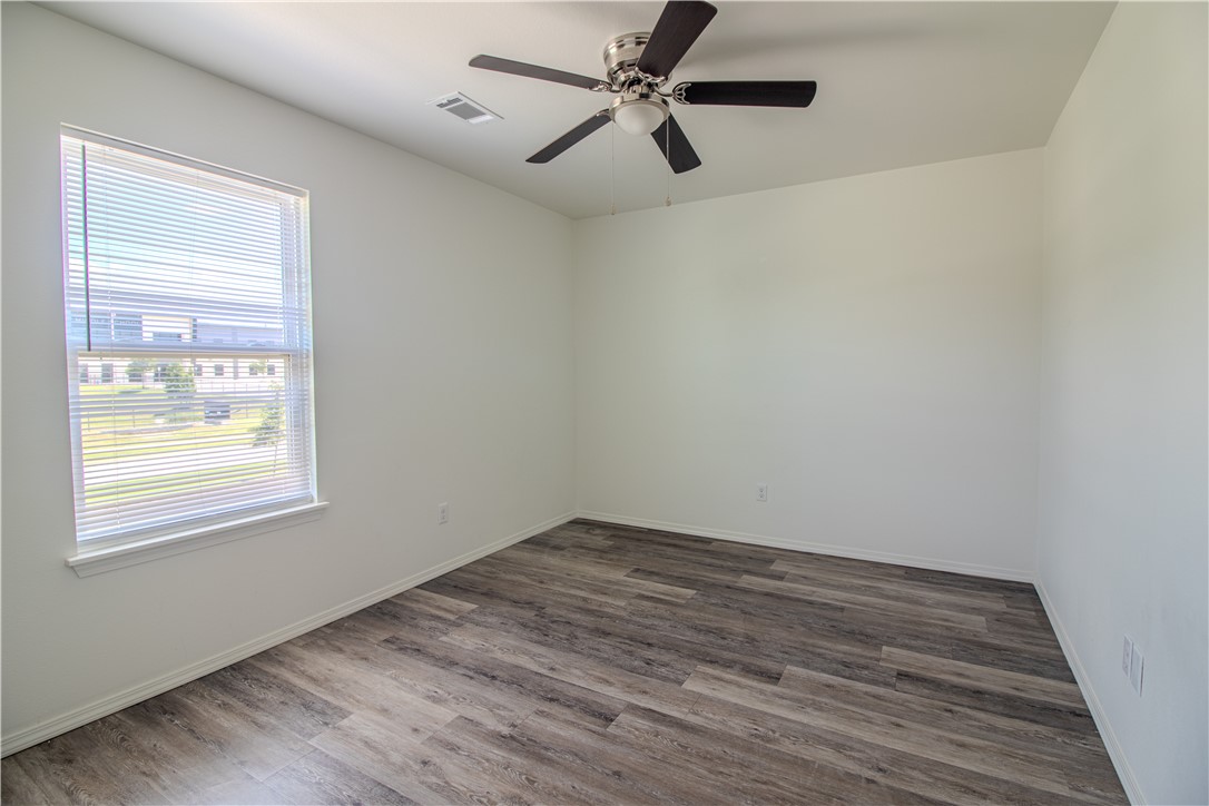 803 South Rupple Road, Unit 1 Fayetteville, AR 72704 - Photo 16 of 22 Bright interior room featuring wood-finish flooring, a single window with horizontal blinds, and a ceiling fan with integrated lighting