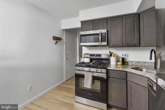 a kitchen with stainless steel appliances granite countertop a stove a sink dishwasher and a refrigerator with wooden cabinets