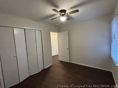 an empty room with wooden floor and fan