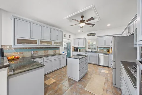 a kitchen with stainless steel appliances granite countertop a sink a stove a refrigerator and cabinets