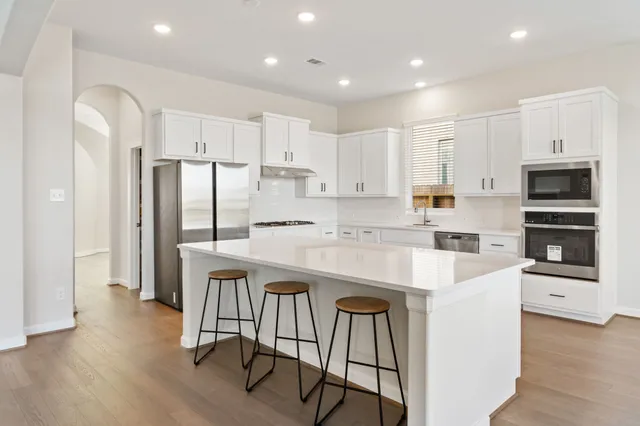 a kitchen with stainless steel appliances granite countertop a refrigerator and a stove top oven