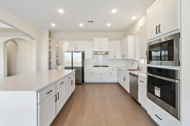 a kitchen with stainless steel appliances kitchen island granite countertop a stove a sink and a refrigerator