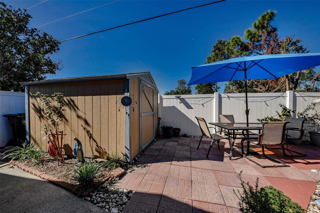 8037 Powder Horn Circle Largo, FL 33773 - Photo 24 of 27 a view of a patio with table and chairs under an umbrella