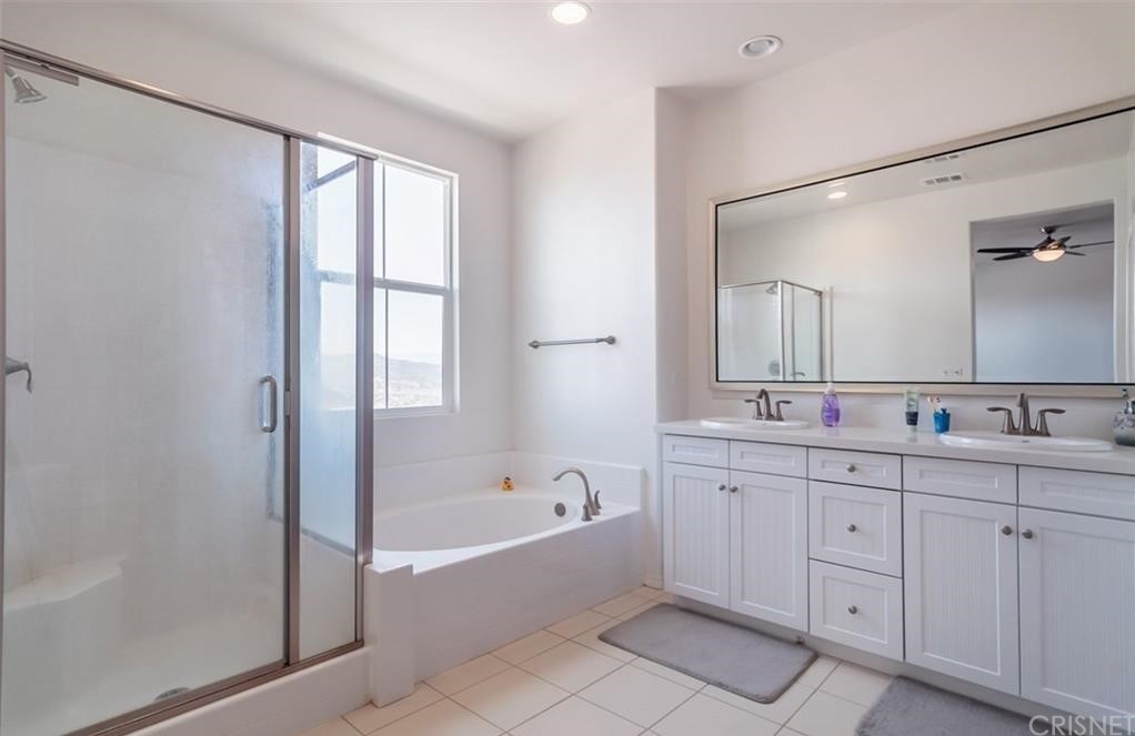 22166 Barrington Way Saugus, CA 91350 - Photo 12 of 19 a spacious bathroom with a double vanity sink a mirror a bathtub and next to a window