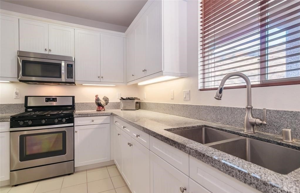 22166 Barrington Way Saugus, CA 91350 - Photo 3 of 19 a kitchen with granite countertop white cabinets a sink and a stove