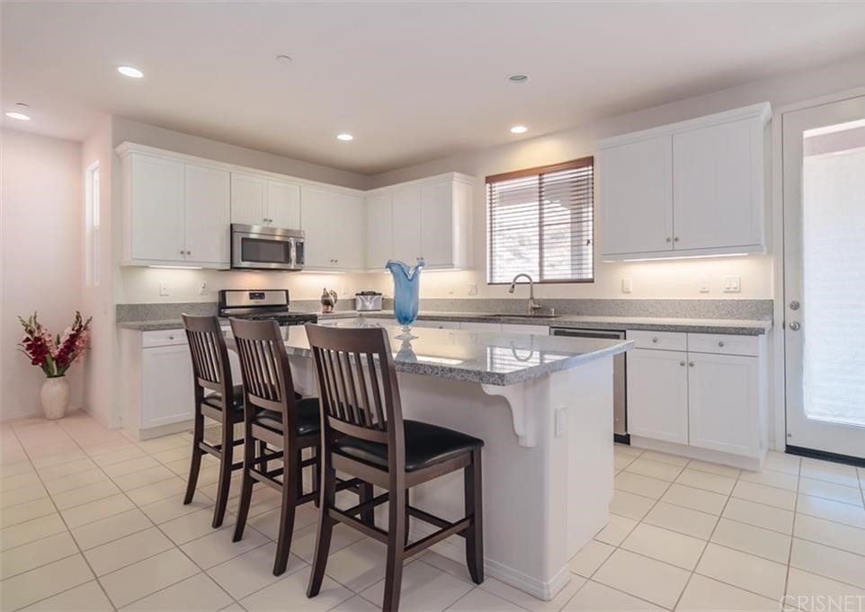22166 Barrington Way Saugus, CA 91350 - Photo 5 of 19 a kitchen with kitchen island granite countertop wooden cabinets and white appliances