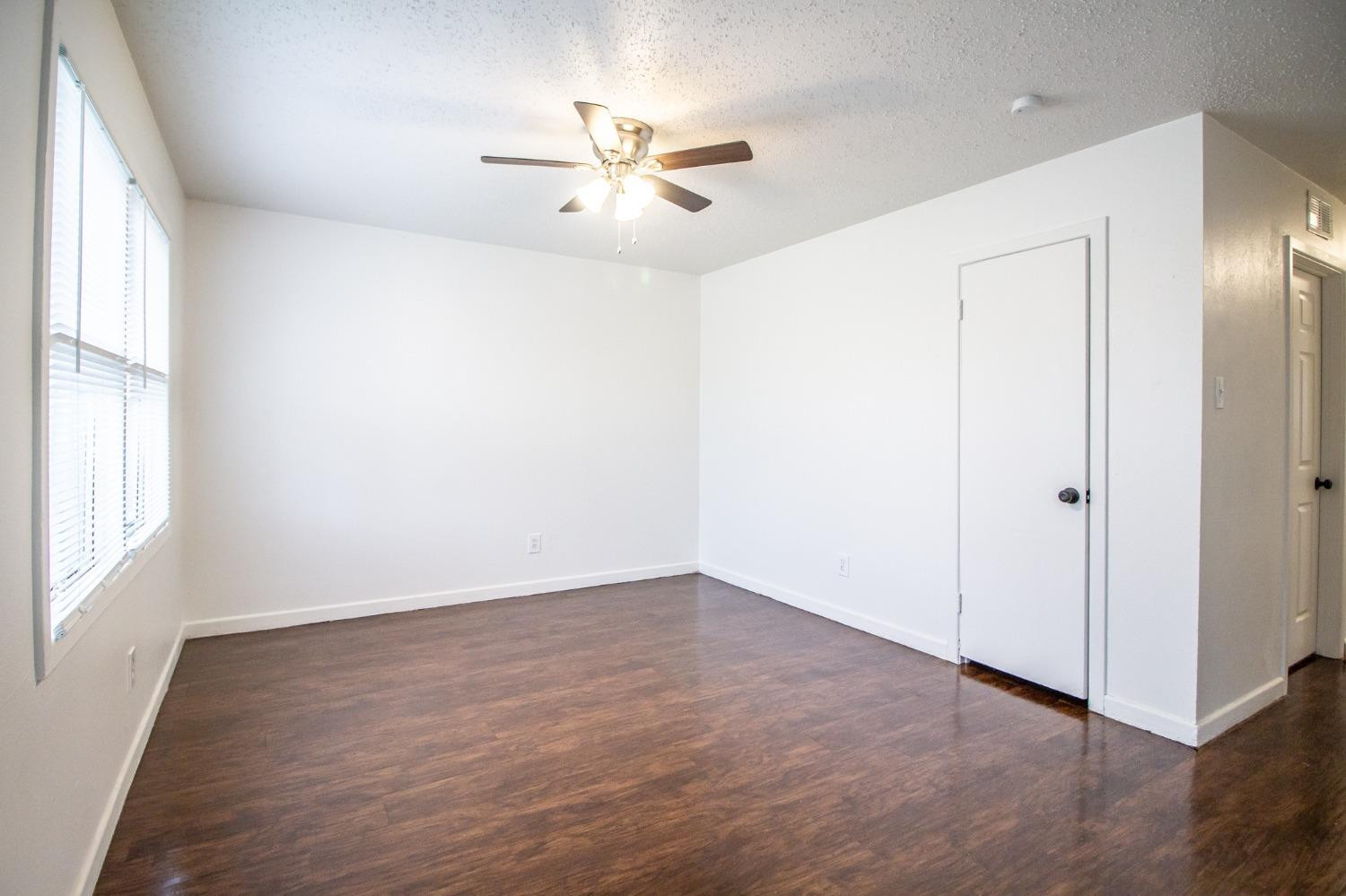 5105 39th Street Lubbock, TX 79414 - Photo 3 of 18 an empty room with wooden floor fan and windows