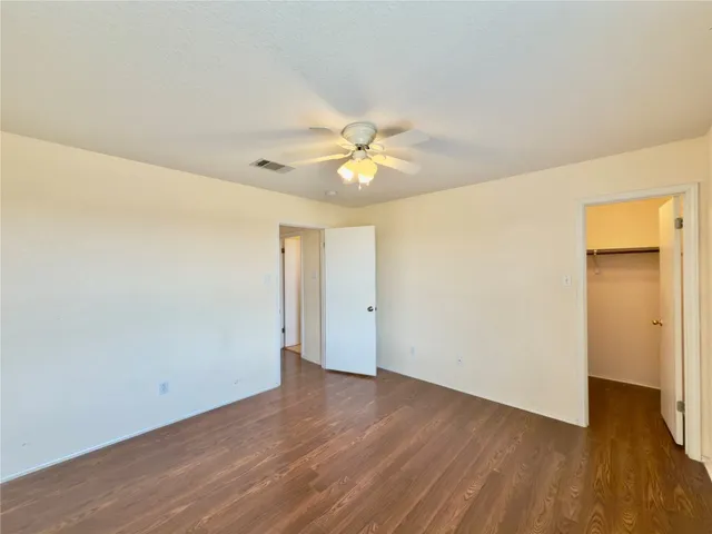 an empty room with wooden floor and a ceiling fan