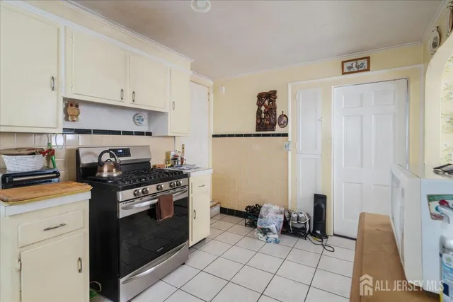 a kitchen with a stove white cabinetry and chairs