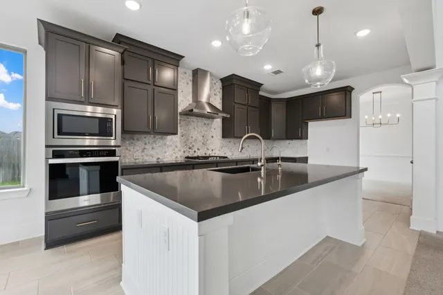 a kitchen with stainless steel appliances granite countertop a sink a microwave and wooden cabinets