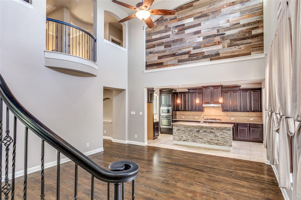 1505 5th Street Argyle, TX 76226 - Photo 9 of 25 a view of a hallway with kitchen island stainless steel appliances refrigerator stove and wooden floor