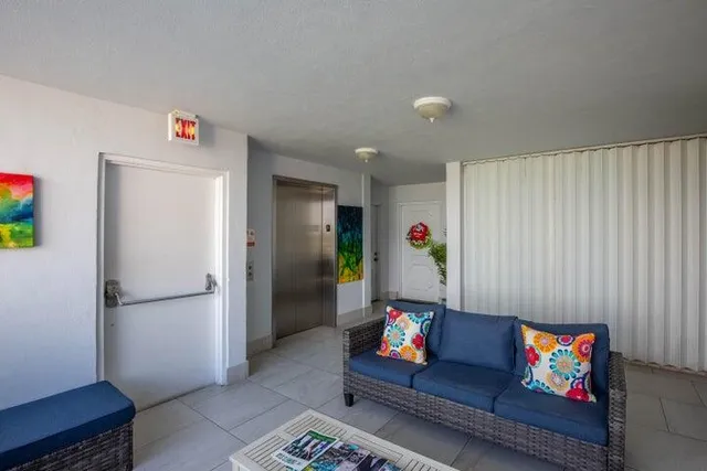 a living room with furniture and a refrigerator