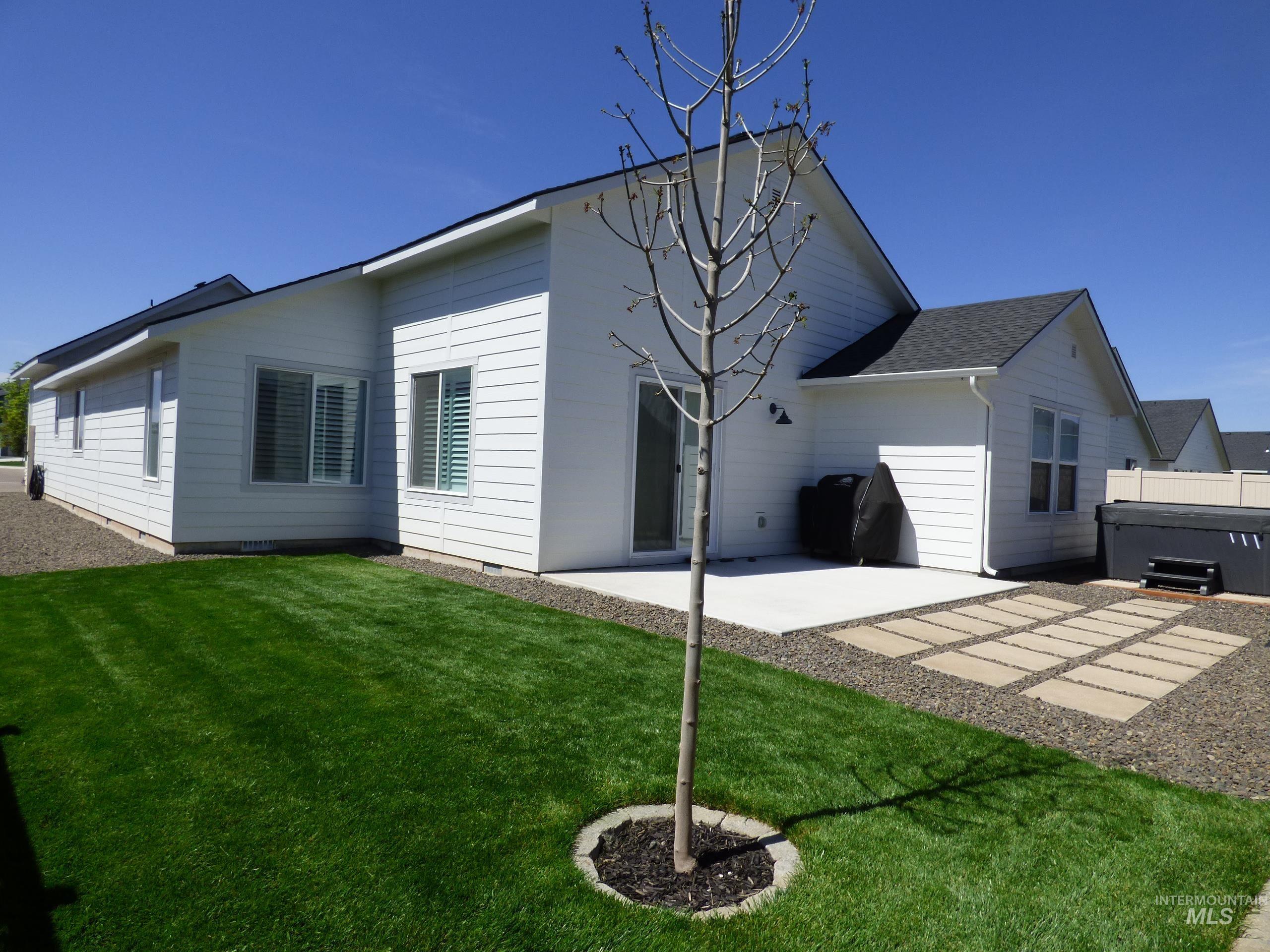 2708 East Buckaroo Drive Kuna, ID 83634 - Photo 39 of 48 Rear exterior featuring white horizontal siding, a sliding glass door, a concrete patio, and a stone paver extension
