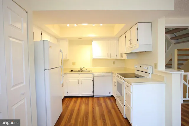 a kitchen with granite countertop white cabinets and white appliances
