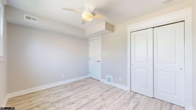 an empty room with wooden floor and fan