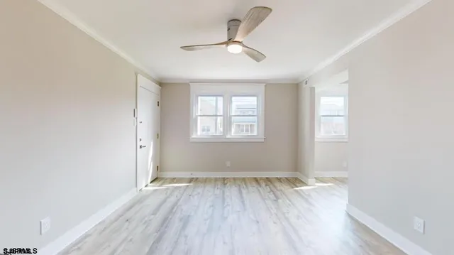 an empty room with wooden floor ceiling fan and windows