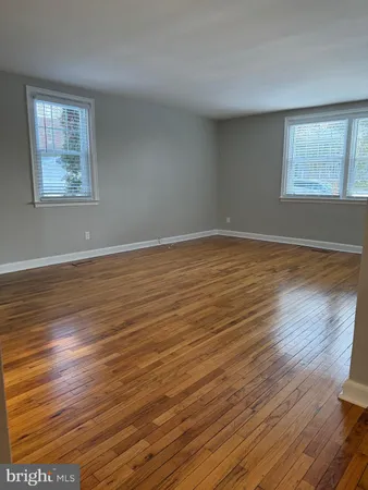 a view of an empty room with wooden floor and closet