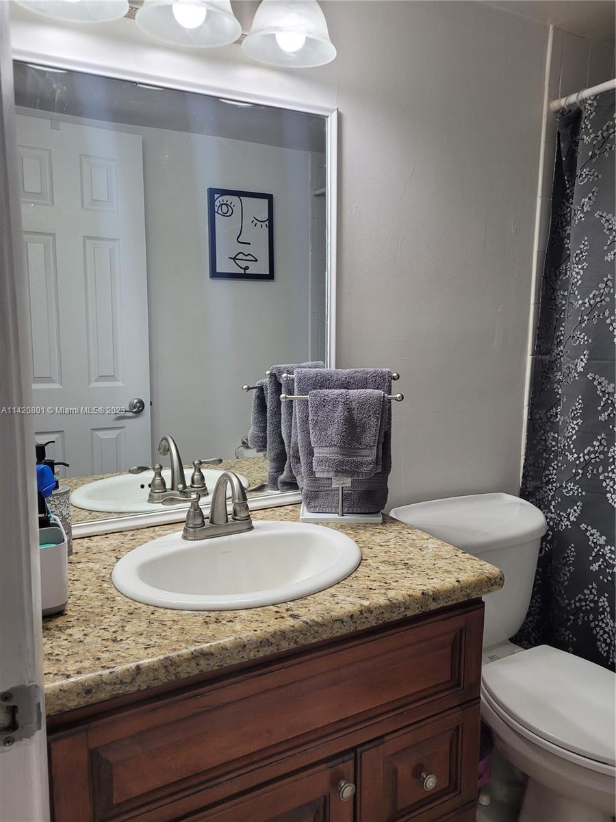 1066 North Hiatus Road, Unit 1066 Pembroke Pines, FL 33026 - Photo 21 of 33 a bathroom with a granite countertop sink a toilet and mirror