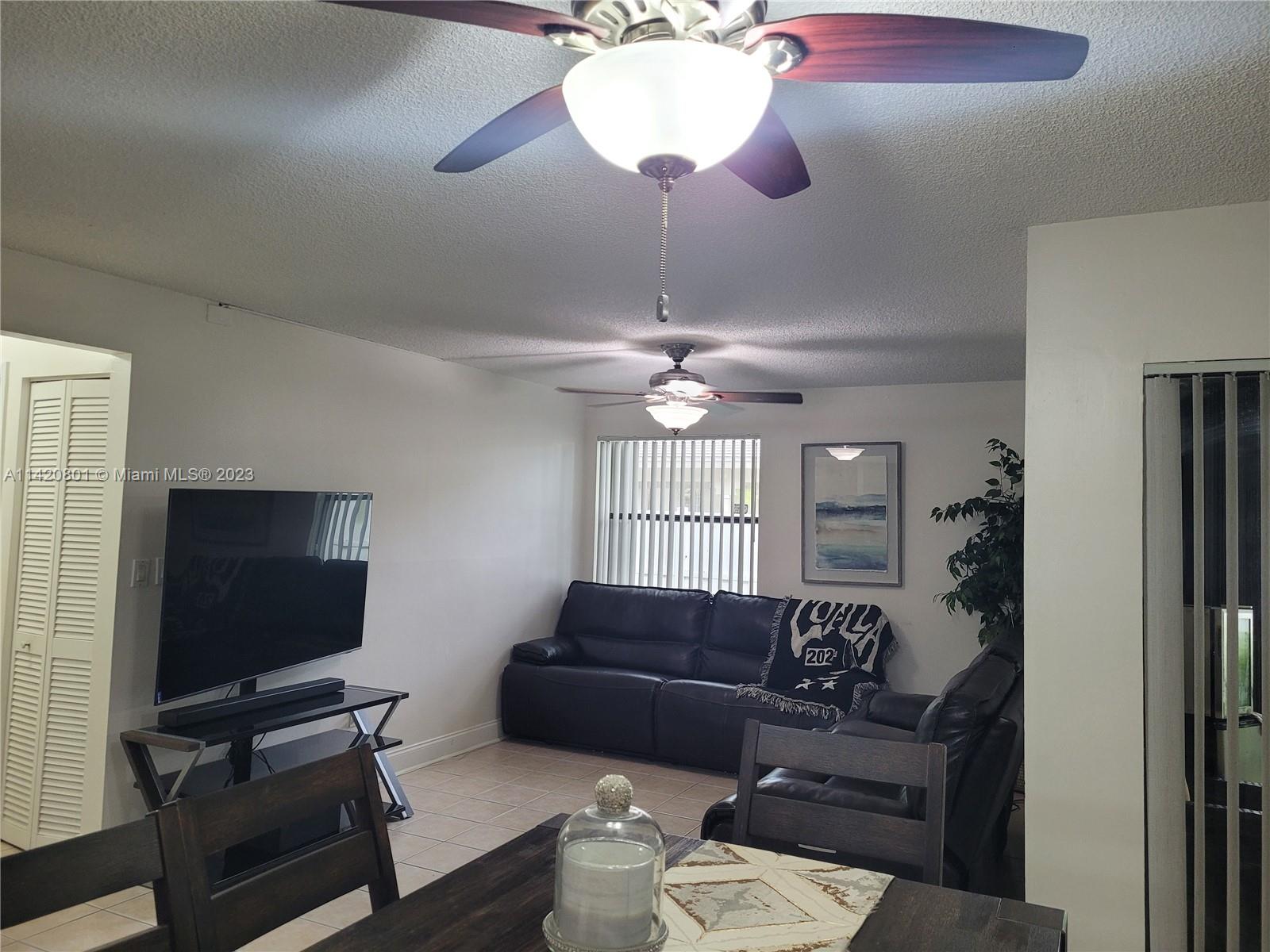1066 North Hiatus Road, Unit 1066 Pembroke Pines, FL 33026 - Photo 4 of 33 a living room with furniture a chandelier and a flat screen tv