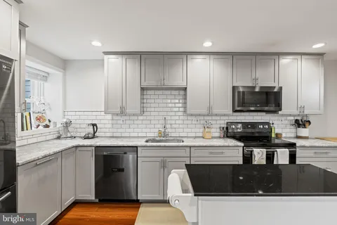a kitchen with stainless steel appliances a sink a stove a microwave a refrigerator and cabinets