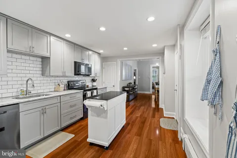 a large white kitchen with wooden floor